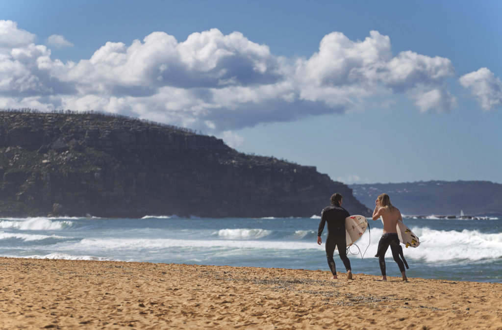 Two surfers talk as they leave the beach