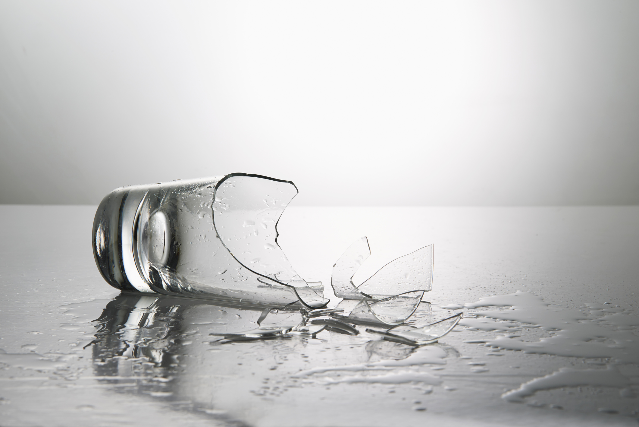 Разбилась стеклянный стакан. Разбитые стаканы. Разбитый стакан с водой. Разлитая вода на столе.