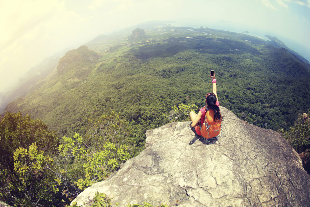 young woman hiker use smartphone taking photo on seaside mountain