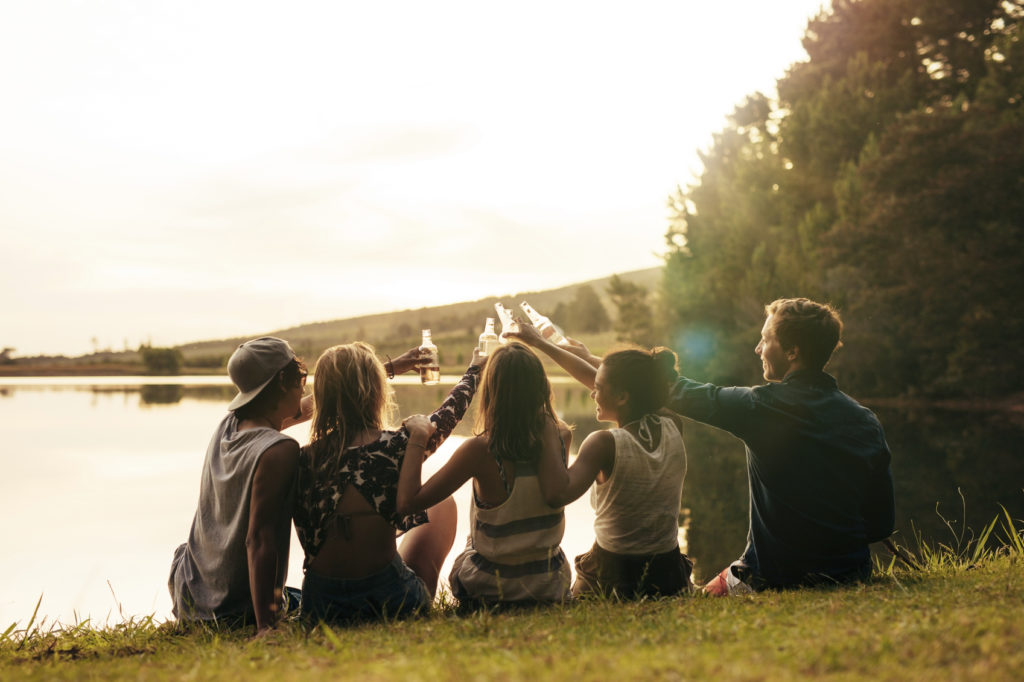 Friends celebrating with beers at the lake