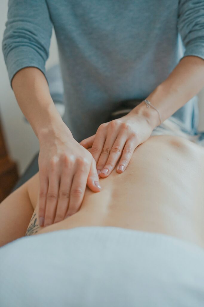 Female hands pressing on pain spot of a man’s back